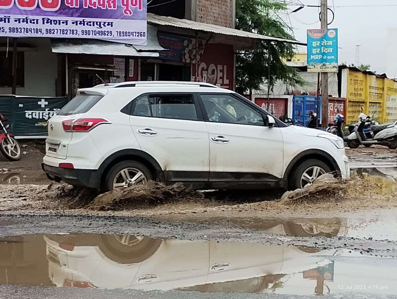 नर्मदा घाट पर जमा हुई मिट्टी सड़कों के गड्ढों में भराया बारिश का पानी